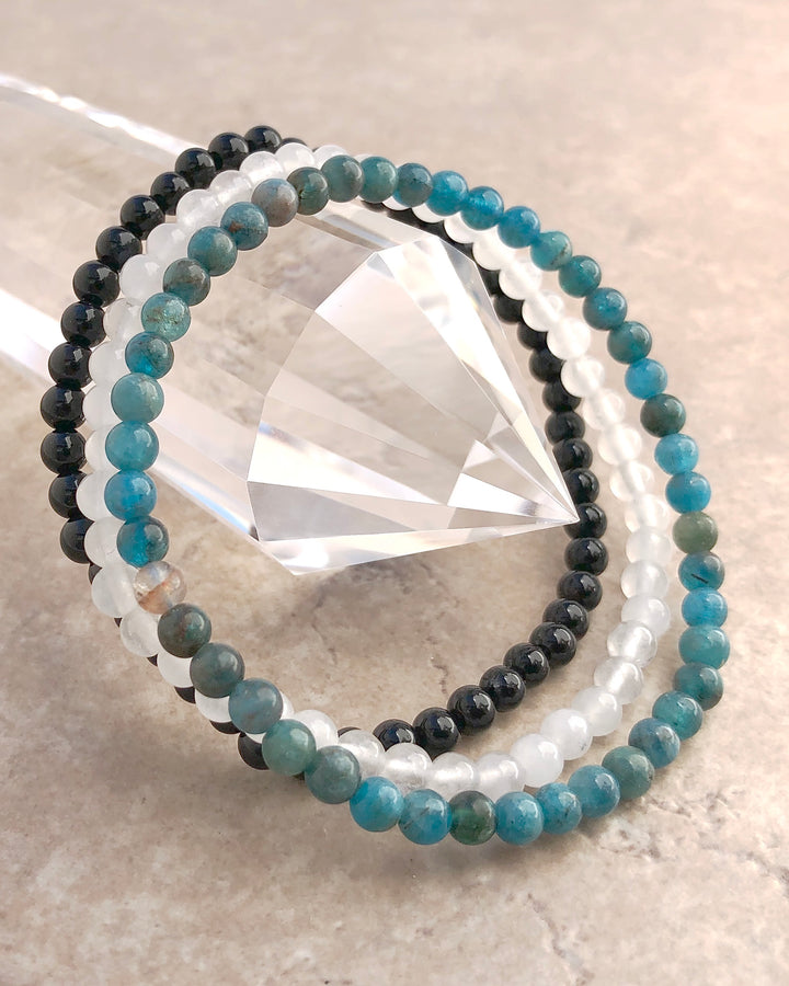 Spiritual Growth 4mm Beaded Gemstone Bracelet Set with Apatite, Snow Quartz and Black Agate Bracelets on a crystal