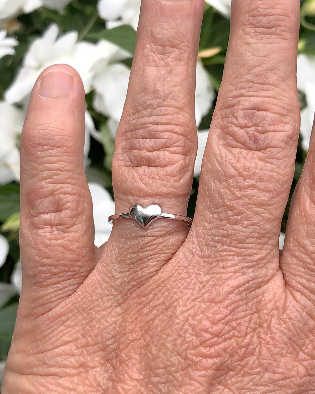 Sterling Silver Heart Ring on finger with white flowers